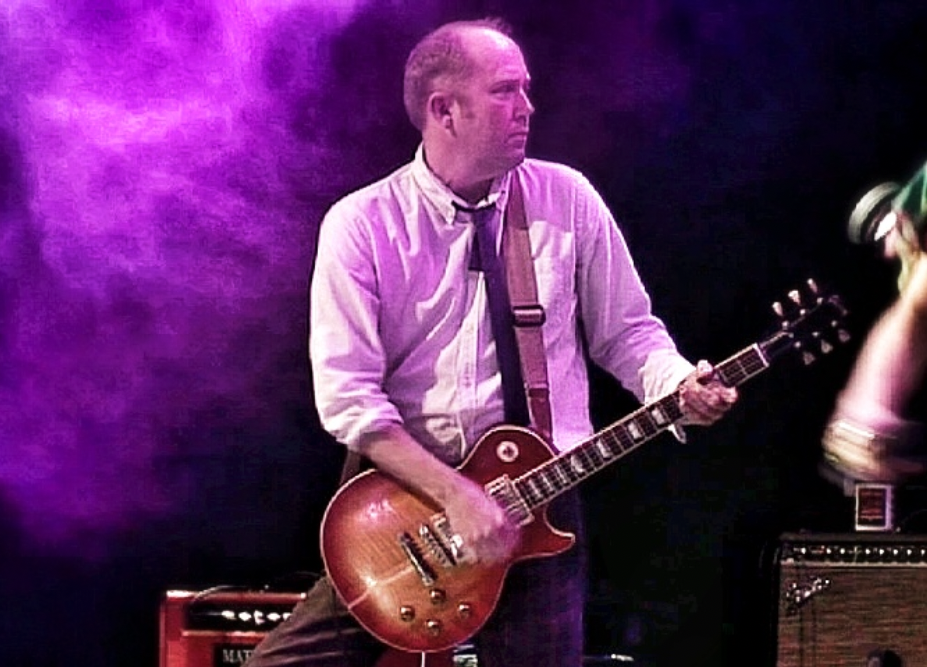Person playing guitar on stage with purple smoke